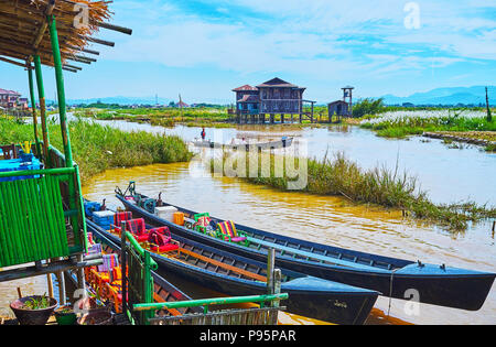 YWAMA, MYANMAR - 18 febbraio 2018: canoe sono ormeggiati a palafitta sul Lago Inle, coperti da boschetti di erbacce, il 18 febbraio in Ywama. Foto Stock