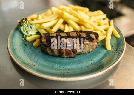 Gara osteria alla griglia o t-bone steak servita con nitide golden patatine fritte e fresco e verde insalata di erbe accompagnato da un BBQ o burro alle erbe aromatiche Foto Stock