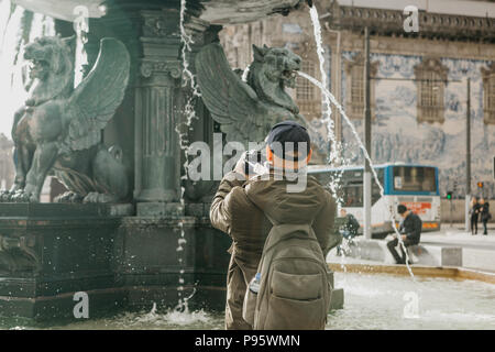 Un fotografo professionista o videografo scatta foto o riprese video di una bella fontana nella piazza di Porto in Portogallo o un turista m Foto Stock