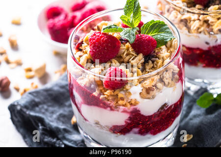 Yogurt parfafait con muesli, marmellata di lamponi e nel vasetto di vetro. Close up. Foto Stock