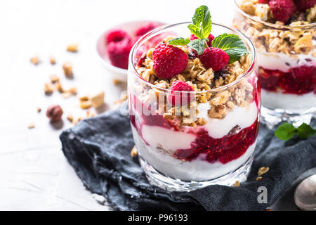 Yogurt parfafait con muesli, marmellata di lamponi e nel vasetto di vetro. Close up. Foto Stock