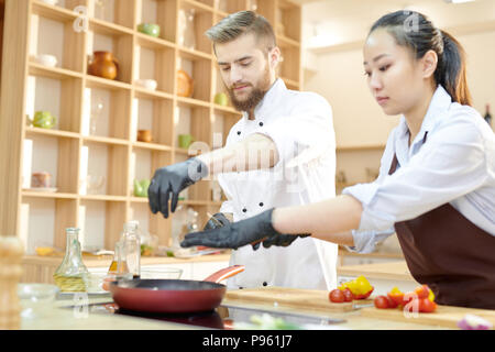 Due giovani chef operanti in cucina Foto Stock