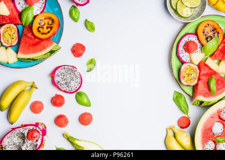 Estate pulito e sano stile di vita con uno sfondo colorato varie fette di frutta tropicale e bacche di piatti e ciotole su sfondo bianco, top vie Foto Stock