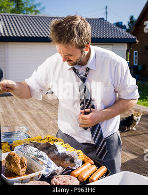 Uomo in camicia e cravatta, per cottura alla brace fuori nel sole durante il norvegese giorno costituzionale celebrazioni. Foto Stock