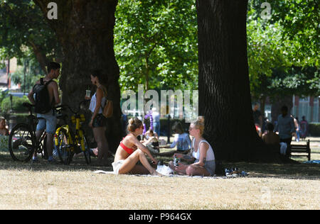 Persone sole in Haggerston Park, a Hackney est di Londra come il clima caldo prosegue attraverso la maggior parte delle parti del Regno Unito. Foto Stock