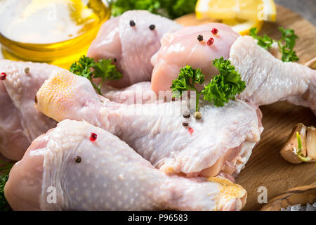 Il pollo crudo bacchette sul tagliere con gli ingredienti per cucinare. Foto Stock