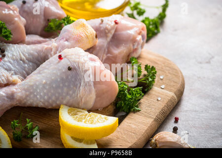 Il pollo crudo bacchette sul tagliere con gli ingredienti per cucinare. Foto Stock