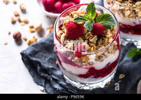 Yogurt parfafait con muesli, marmellata di lamponi e nel vasetto di vetro. Close up. Foto Stock