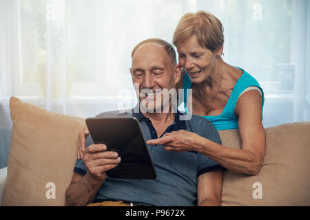 Felice coppia senior con tavoletta digitale in casa Foto Stock