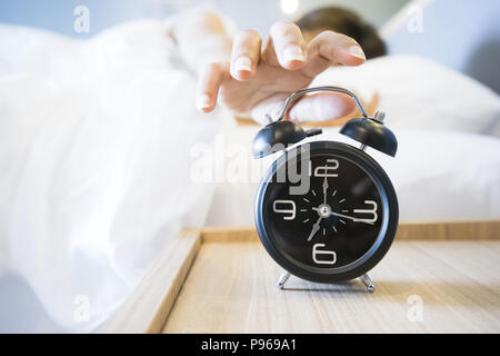 Donna addormentata nel letto di spegnere la sveglia, il fuoco selettivo Foto Stock