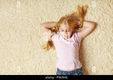 In età scolare ragazza distesa su un tappeto Foto Stock