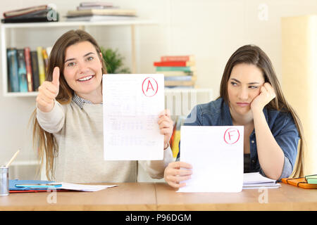 Vista frontale ritratto di due studenti che mostra non è riuscita e ha approvato gli esami a casa Foto Stock