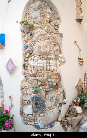 SPERLONGA, Italia - 29 aprile 2018. La parete nella piccola strada a Sperlonga decorato con pietre e ceramiche. Destinazione famosa per i turisti Foto Stock