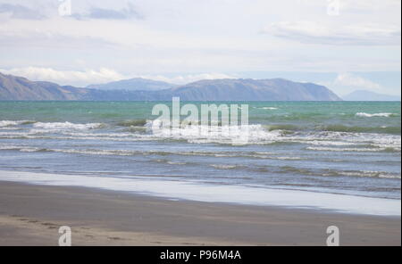 Le onde in arrivo sul Raumati Beach guardando fuori verso Pukerua Bay e Porirua in basso sulla costa ovest dell'Isola del nord della Nuova Zelanda. Foto Stock