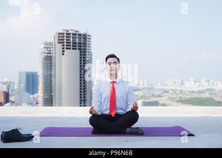 Un giovane imprenditore asiatici facendo sport a tetto Foto Stock