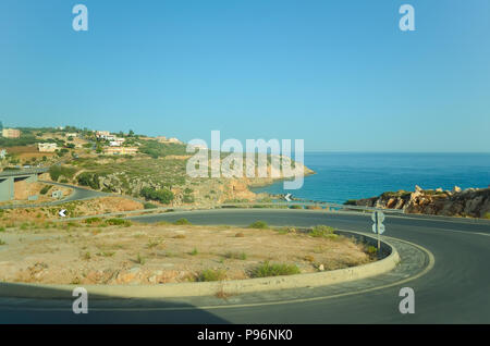 Un avvolgimento strada asfaltata lungo la costa del mare in Grecia. Foto Stock