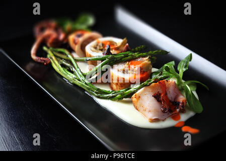 Arrosto di calamari con gamberi e asparagi, poggiante su salsa di patate. Foto Stock