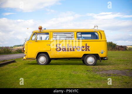 Giallo Volkswagen camper van con logo Saltrock dipinta sulla fiancata Foto Stock