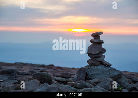 Close-up immagine astratta di grezzo marrone naturale disuniformità di diverse dimensioni e forme delle pietre di montagna bilanciati come pyramid pila sul brillante luce copia blu s Foto Stock