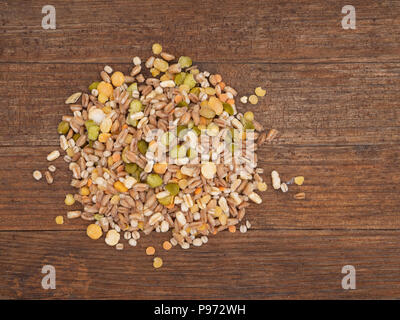 Un assortimento di cereali e legumi mix su legno rustico scheda, vista aerea. Inverno include alimentari Piselli spezzati, rosso e giallo di lenticchie, farro, kamut, il farro. Foto Stock