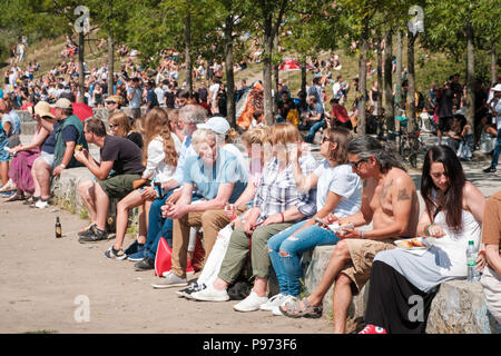 Berlino, Germania - Luglio 2018: Molte persone sedute insieme a bere nelle affollate Park (Mauerpark) su una soleggiata giornata estiva Foto Stock