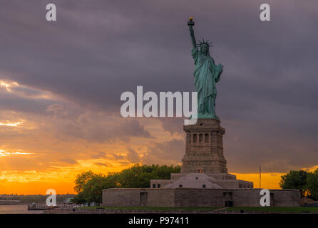 Vista al tramonto della statua della libertà nel porto di New York Foto Stock