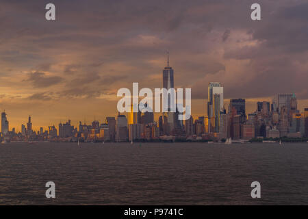 Bellissima la luce del tramonto illumina New York skyline della città con molte barche a vela passando sulla East River Foto Stock