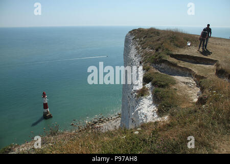 Beachy Head, Regno Unito - 14 Luglio 2018: Visto turistico su Beachy Head scogliera che domina il Beachy Head Lighthouse 162 metri più in basso in una calda giornata estiva il 14 luglio 2018. Temperature sollevato a 27 gradi e si prevede di rimanere alta per un altro mese. La scogliera, il più alto di chalk scogliera sul mare in Gran Bretagna sorge a 162 metri sopra il livello del mare e purtroppo uno dei più famosi punti di suicidio in tutto il mondo. Credito: David Mbiyu Foto Stock