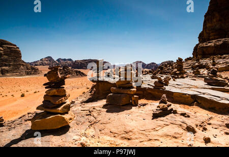 Vista da Lawrence's Castle Rock cliff attraverso Wadi Rum desert valley con inukshuks o lucci di pietre, Giordania, Medio Oriente Foto Stock