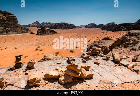 Vista da Lawrence's Castle Rock cliff attraverso Wadi Rum desert valley con inukshuks o lucci di pietre, Giordania, Medio Oriente Foto Stock