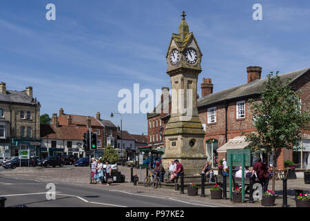 La Piazza del Mercato con il Villaggio Orologio su una soleggiata giornata estiva; Thirsk, North Yorkshire, Regno Unito Foto Stock