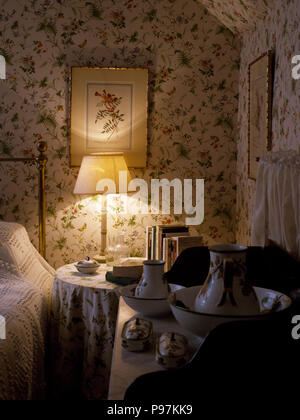Lampada accesa sul comodino in stile vittoriano, camera da letto con carta da parati floreale Foto Stock