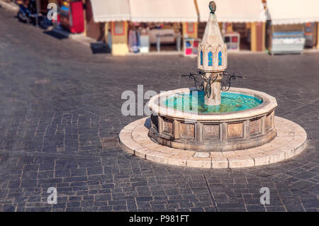 Bella Fontana pubblica nella città di Rodi di isola greca con marmo scuro strada di blocco Foto Stock