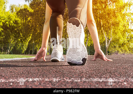 Atleta donna in esecuzione di avviare pongono sulla strada della citta'. Sport vestiti stretti. Calzature sportive in primo piano, vista posteriore. Foto Stock