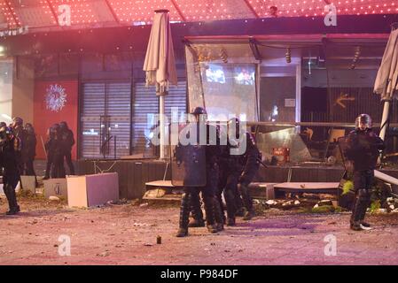 Parigi, Francia. Il 15 luglio 2018.Francese di polizia antisommossa stand protezione nella parte anteriore del Publicis Drugstore sul Champs-Elysees, che è stato aggredito in scia di Coppa del Mondo di celebrazioni. Des policiers montent la garde devant le Drugstore Publicis sur les Champs Elysees. La boutique a ete attaquee lors des celebrazioni de la Victoire de la France dans la Coupe du Monde. *** La Francia / nessuna vendita di supporti in francese.Credit: Fotografia Idealink/Alamy Live News Foto Stock