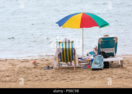 Bournemouth, Dorset, Regno Unito. 16 luglio 2018. Tempo nel Regno Unito: Incantesimi soleggiati a Bournemouth, ma con una copertura di nuvole in aumento, mentre gli amanti del sole si dirigono verso il mare a Bournemouth spiagge per godersi il bel tempo prima che si rompa. Chi cerca il sole in sedia a sdraio e lettino con ombrellone a Bournemouth spiaggia, sdraio. Credit: Carolyn Jenkins/Alamy Live News Foto Stock