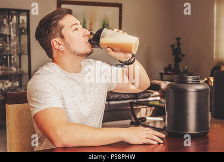 Uomo di bere la proteina del siero di latte alla coppa di miscelazione. Post Allenamento proteine. Supplemento per gli atleti. Foto Stock