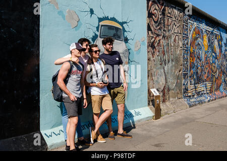 Berlino, Germania - Luglio 2018: un gruppo di giovani uomini di prendere foto di gruppo al muro di Berlino / East Side Gallery di Berlino Foto Stock