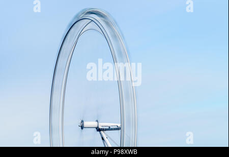 Una lunga esposizione vista della metà superiore del London Eye ruota panoramica sulla South Bank di Londra che figurano a girare rapidamente contro un cielo blu Foto Stock