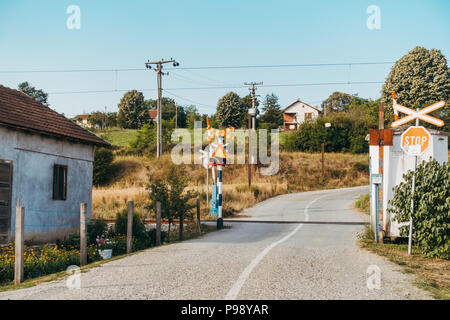 Una piccola casa con un orto, accanto ad una traversata ferroviaria nella campagna serba Foto Stock