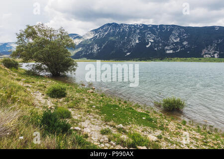 Un nuvoloso giorno accanto alle acque calme di Blidinje Jezero, il più grande lago della Bosnia ed Erzegovina Foto Stock