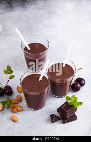 Frullati di cioccolato con ciliegie e mandorle. su un tavolo di pietra grigia. Vegano drink di proteine per gli atleti e i buongustai Foto Stock