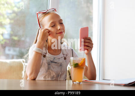 La scolaretta moderno di guardare video mentre è seduto in cafe Foto Stock