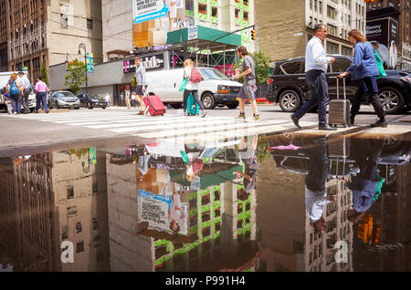 La città di New York, Stati Uniti d'America - 28 Giugno 2018: la gente camminare attraverso il passaggio pedonale si riflette in una pozza in Midtown Manhattan. Foto Stock