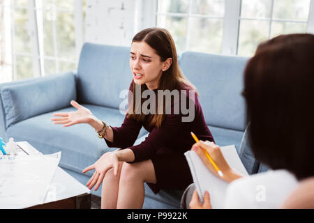 Paziente espressiva utilizzando gesti e parlare alla sua psicologo Foto Stock