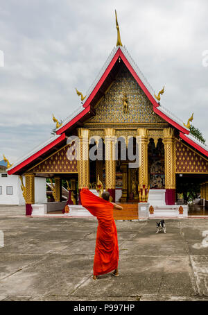 Giovane monaco buddista regola la Sua tonaca arancione al Wat Mahathat tempio a Luang Prabang, Laos Foto Stock