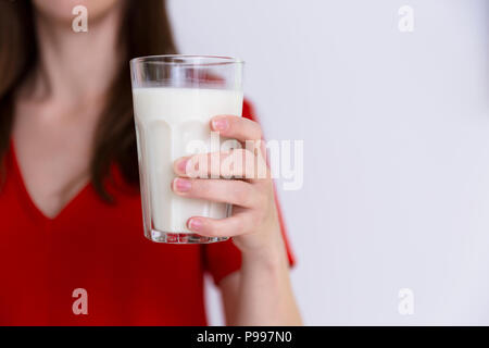 Donna in abito rosso tenendo un bicchiere di latte. L'intolleranza al lattosio, latte di vacca, il concetto di salute Foto Stock