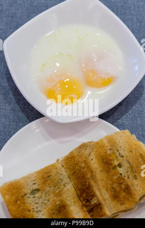 Tradizionale colazione Singapore chiamato Kaya toast, pane di cocco con marmellata e metà uova sode, selettivo tecnica di messa a fuoco Foto Stock