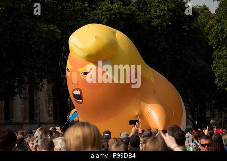 'STOP TRUMP' marcia di protesta in piazza del Parlamento giardini come un arrabbiato caricatura del presidente Donald Trump affacciata alla folla. Londra, UK 13/7/18. Foto Stock