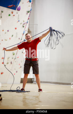 Immagine dell uomo di sport in abbigliamento sportivo e con il cavo di protezione vicino alla parete di arrampicata Foto Stock